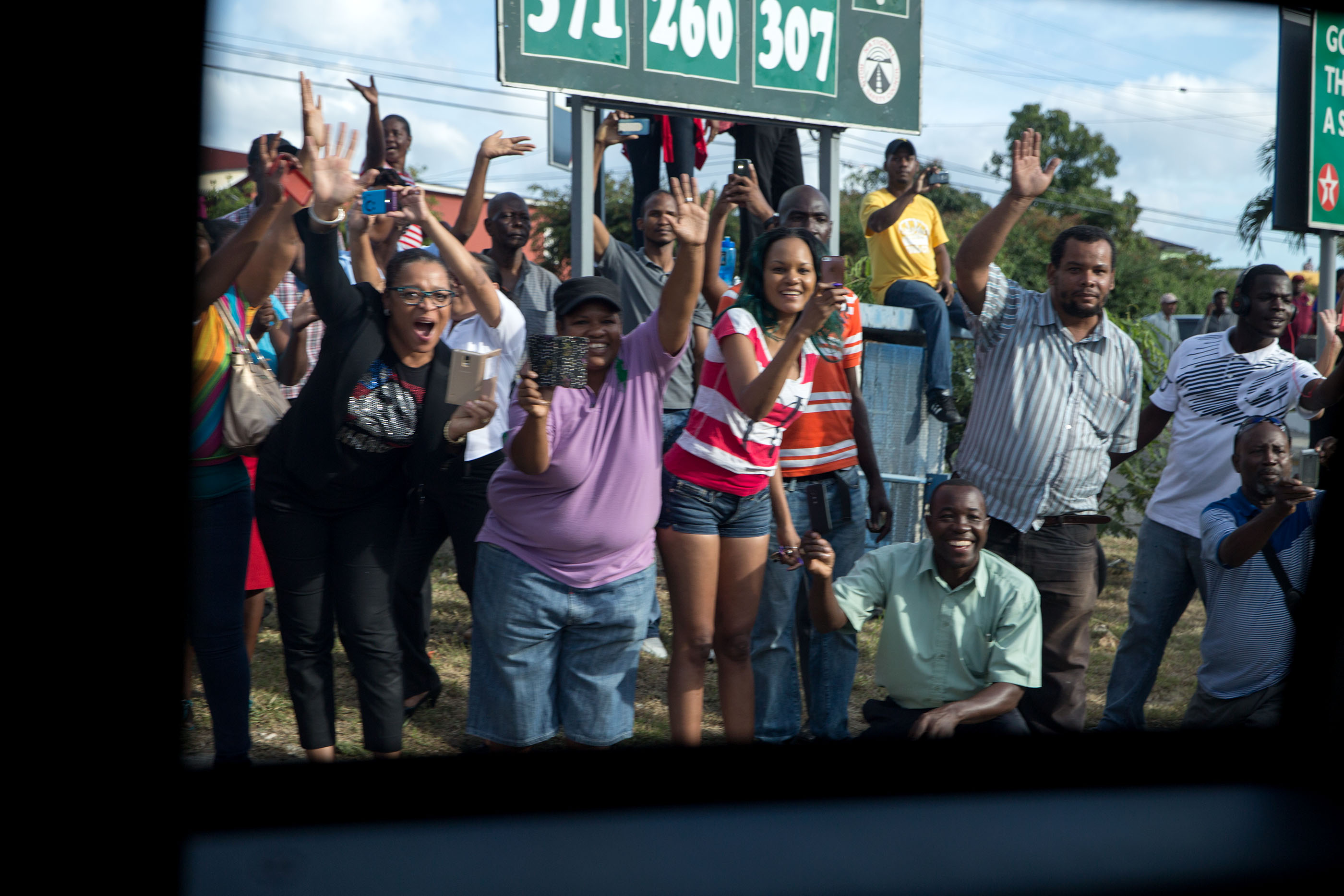 Jamaicans wave at the passing motorcade. (Official White House Photo by Pete Souza)