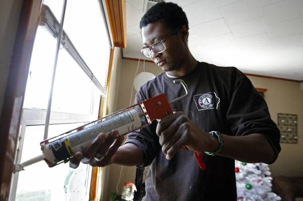 Brandon Gibbs, a Green Iowa AmeriCorps member, caulks the edges of a window frame in a home he is weatherizing in Dubuque, Iowa.