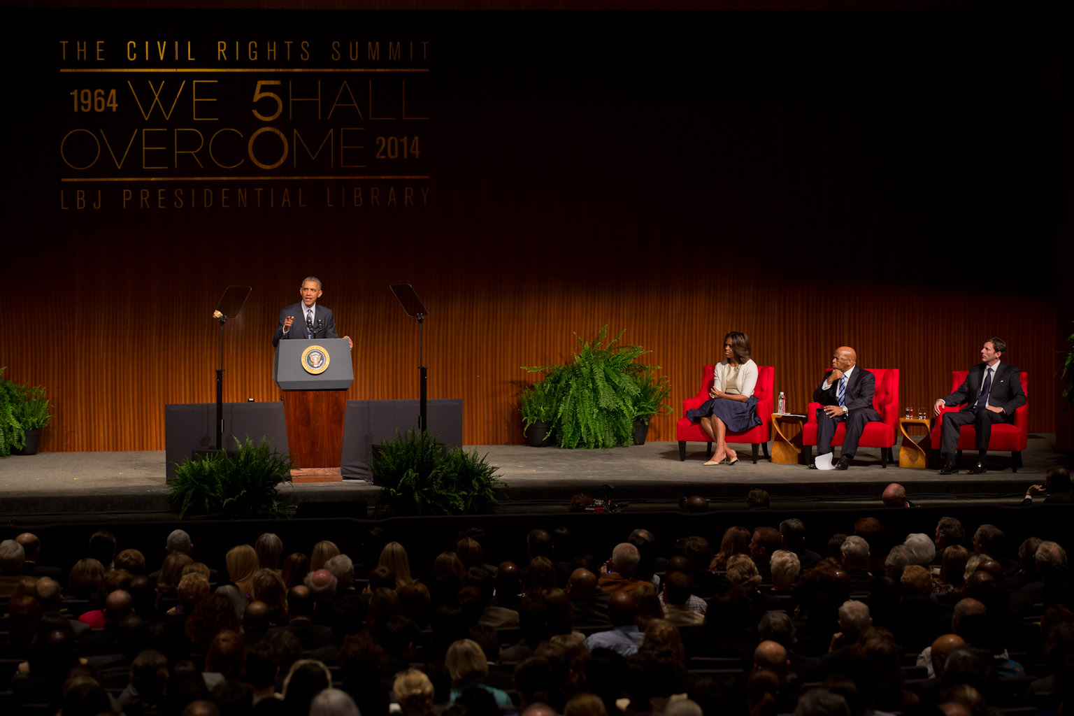 President Barack Obama delivers remarks as First Lady Michelle Obama, Rep. John Lewis, D-Ga., and LBJ Presidential Library Director Mark Updegrove, listen at right at the LBJ Presidential Library