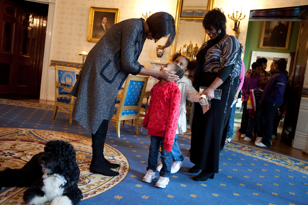  First Lady greets a young visitor touring the White House during a surprise visit in the Blue Room with family dog Bo