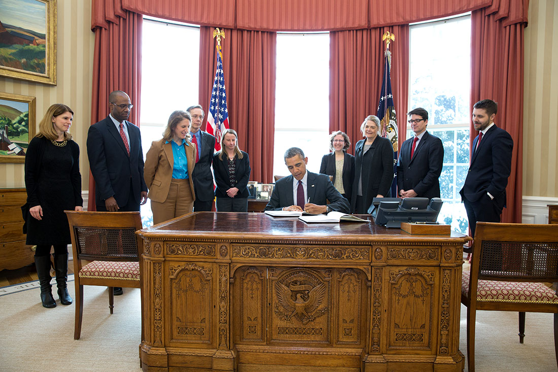 President Barack Obama signs copies of the FY 2015 Budget as Sylvia Mathews Burwell, Director, Office of Management and Budget, and OMB staff look on in the Oval Offic