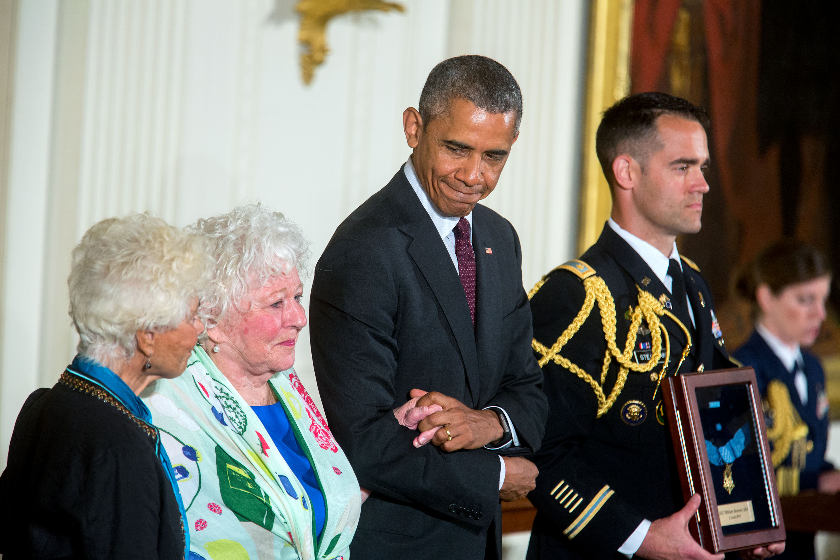 President Barack Obama stands with Ina Judith Bass (left) and Elise Shemin-Roth as the citation is read awarding the Medal of Honor posthumously to their father, Army Sergeant William Shemin, for conspicuous gallantry during World War I, at a ceremony in 