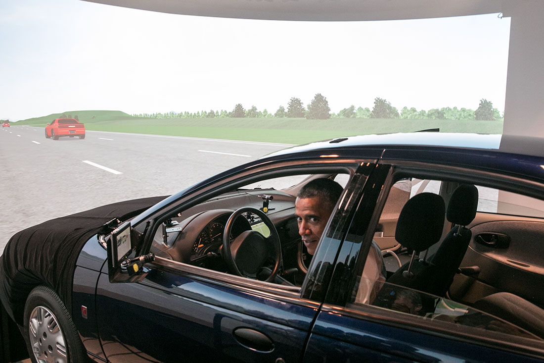 President Barack Obama prepares to drive a Saturn SL1 vehicle simulator