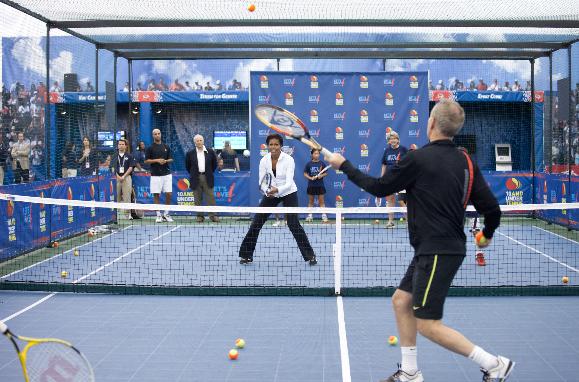 First Lady Michelle Obama hits tennis balls with John McEnroe