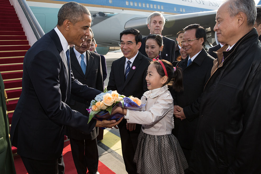 President Barack Obama is presented with a bouquet of flowers by a young Chinese girl upon arrival at Capital International Airport, Beijing
