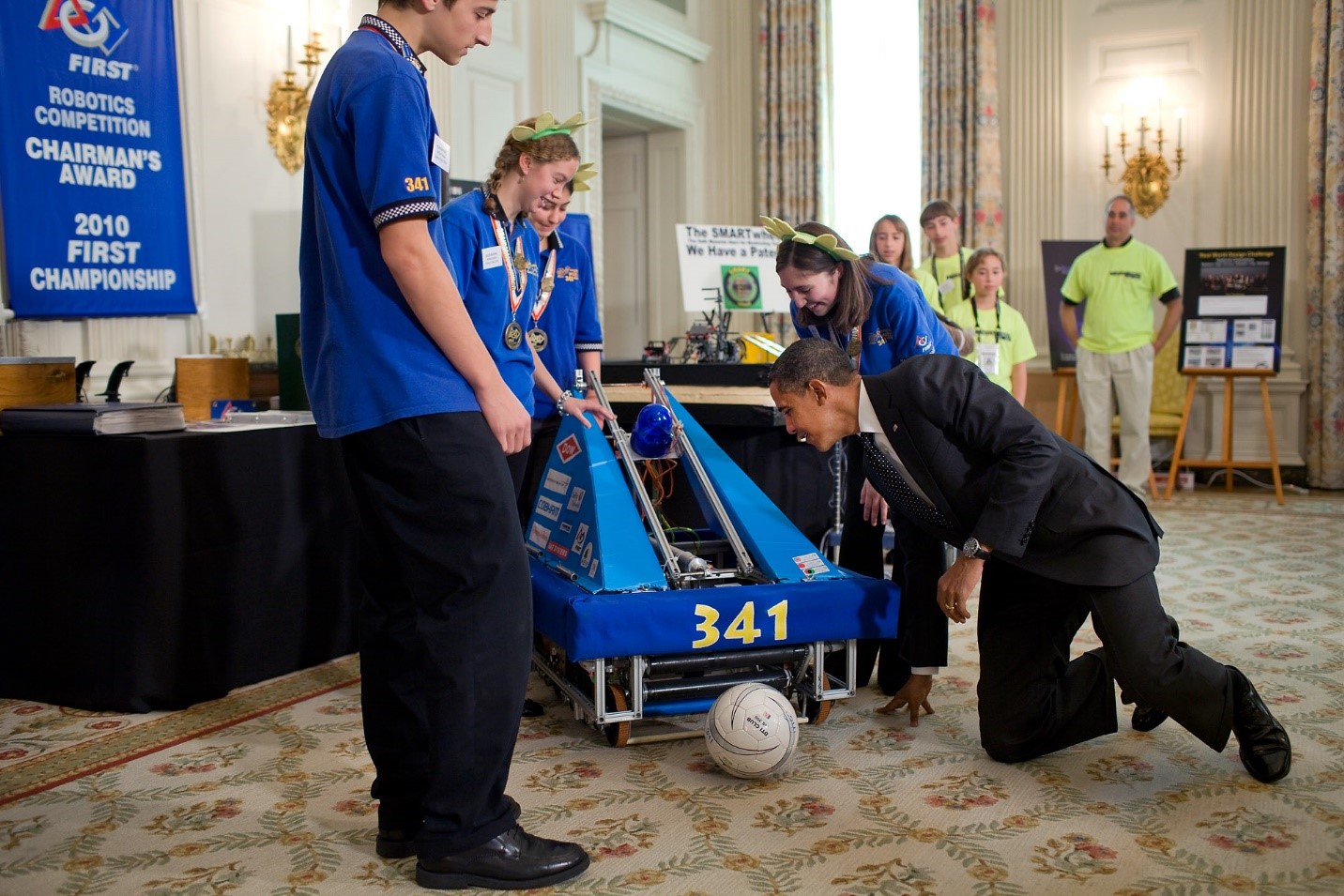 President Barack Obama gets down on his hands and knees as he looks at the inner workings of a robot that plays soccer, built by a team from Blue Bell, Pa., as he tours science projects on display in the State Dining Room of the White House. President Obama hosted the White House Science Fair for winners of a broad range of science, technology, engineering and math (STEM) competitions. October 18, 2010. (Official White House Photo by Pete Souza)