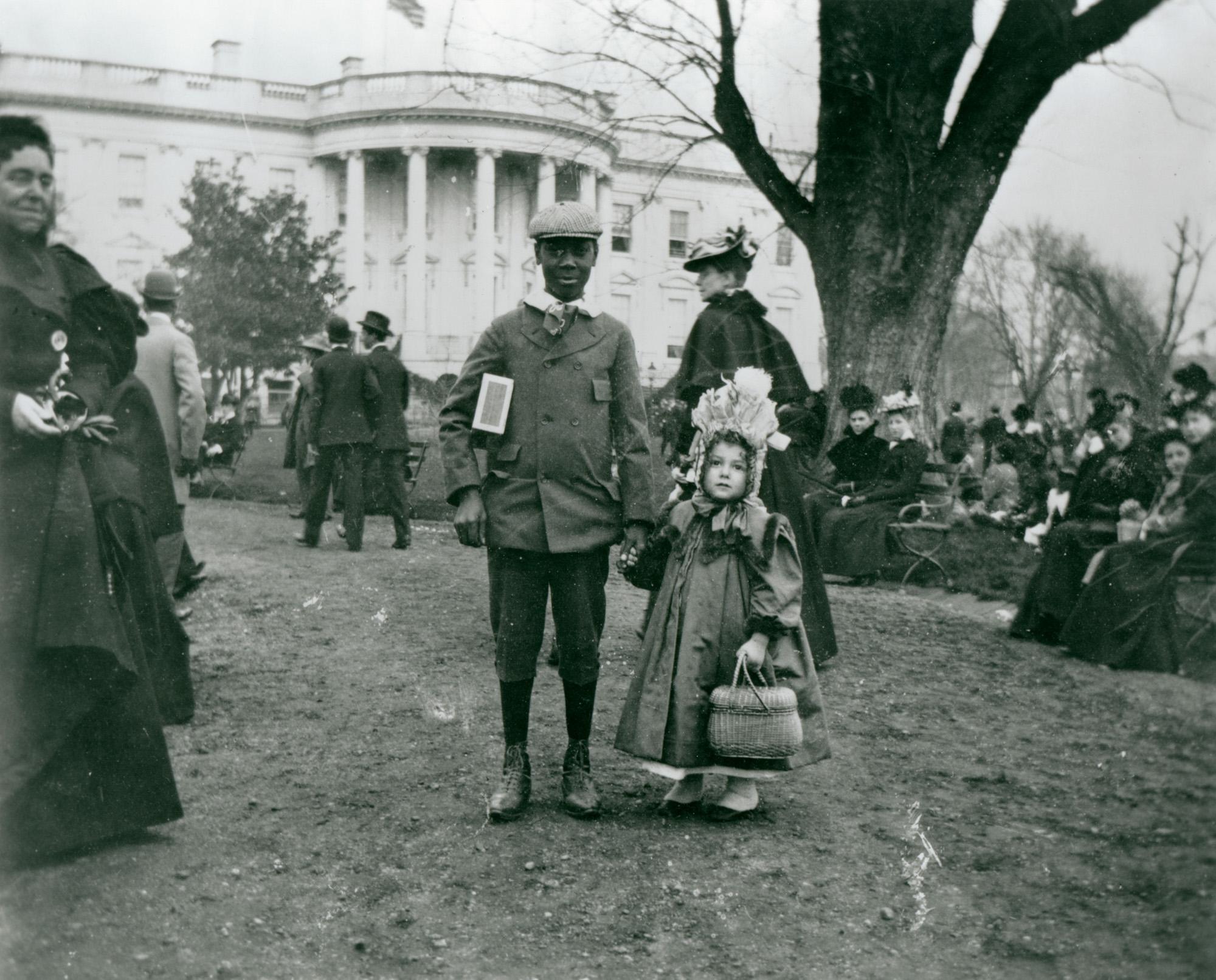 In this photograph taken by Francis Benjamin Johnston in 1898, a boy and a girl hold hands during the annual White House Easter Egg Roll. (1898) (Library of Congress)