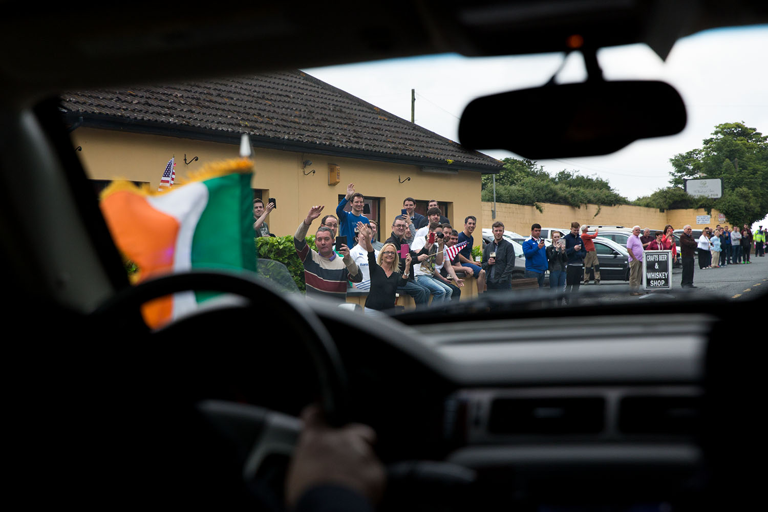 People waving american flags outside a pub along the motorcade route in County Louth, Ireland, June 25, 2016. (Official White House Photo by David Lienemann)