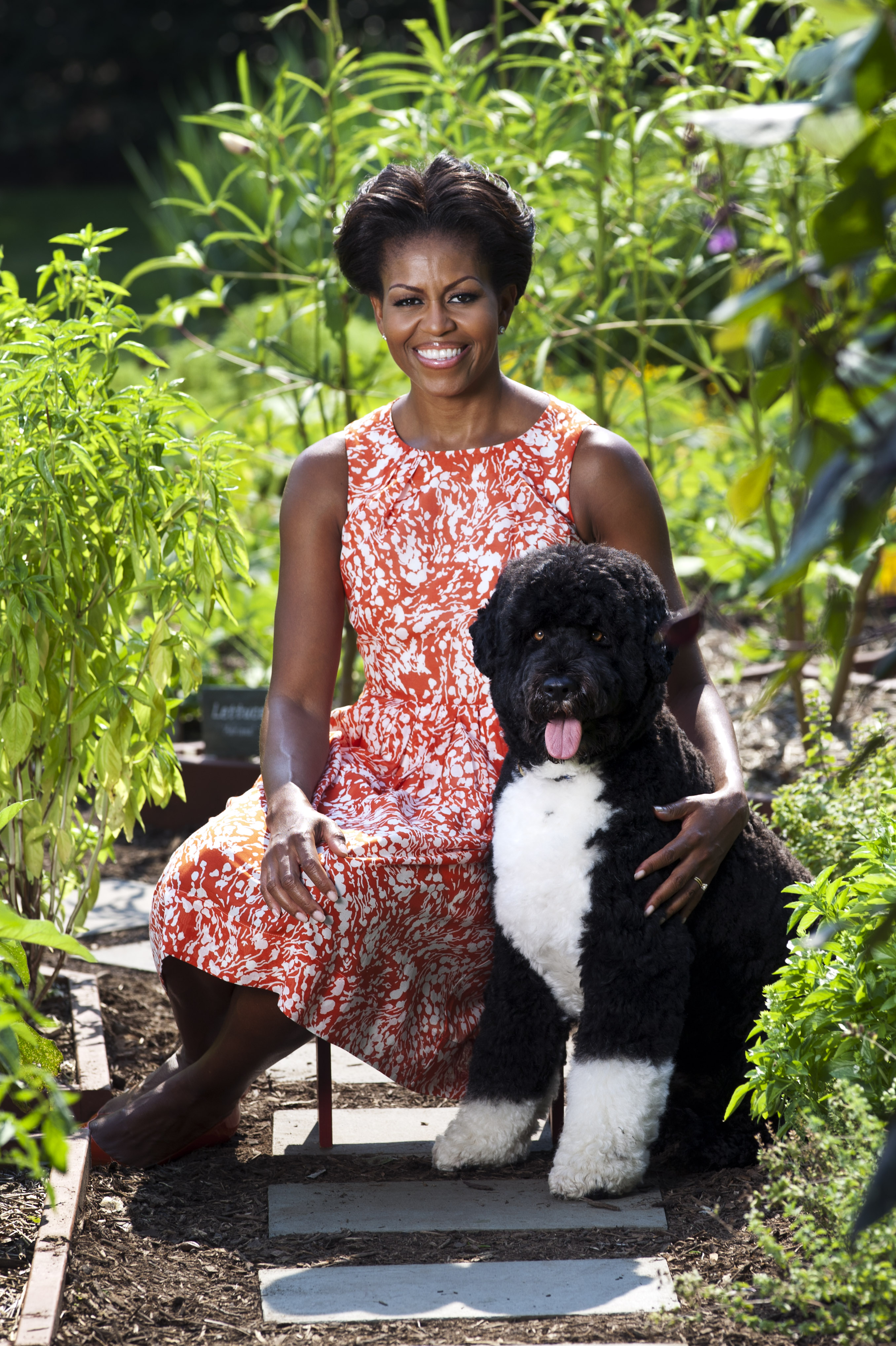 First Lady Michelle Obama sits for a photo with Bo, the first family's dog, in the White House Kitchen Garden.