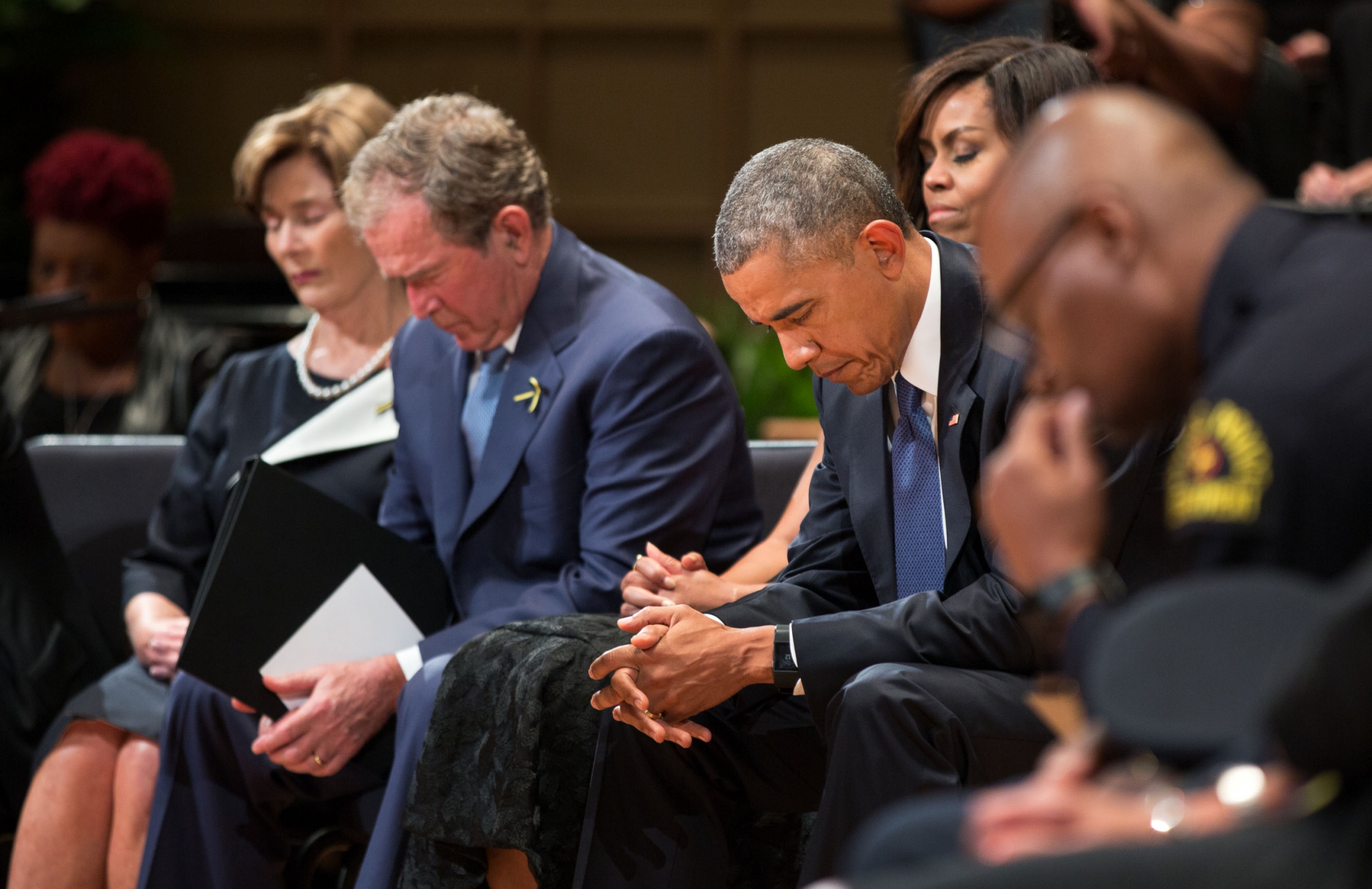 President Barack Obama, First Lady Michelle Obama, former President George W. Bush and former First Lady Laura Bush bow their heads during a prayer at the Interfaith Memorial Service for five fallen police officers in Dallas, Texas, July 12, 2016. Dallas Police Chief David Brown is at right. (Official White House Photo by Pete Souza)