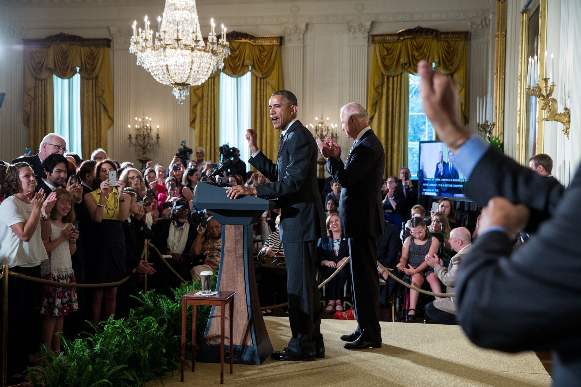 An interpreter signs in the foreground while President Barack Obama, with Vice President Joe Biden, delivers remarks during a reception for the 25th anniversary of the Americans with Disabilities Act (ADA) in the East Room of the White House, July 20, 2015. 