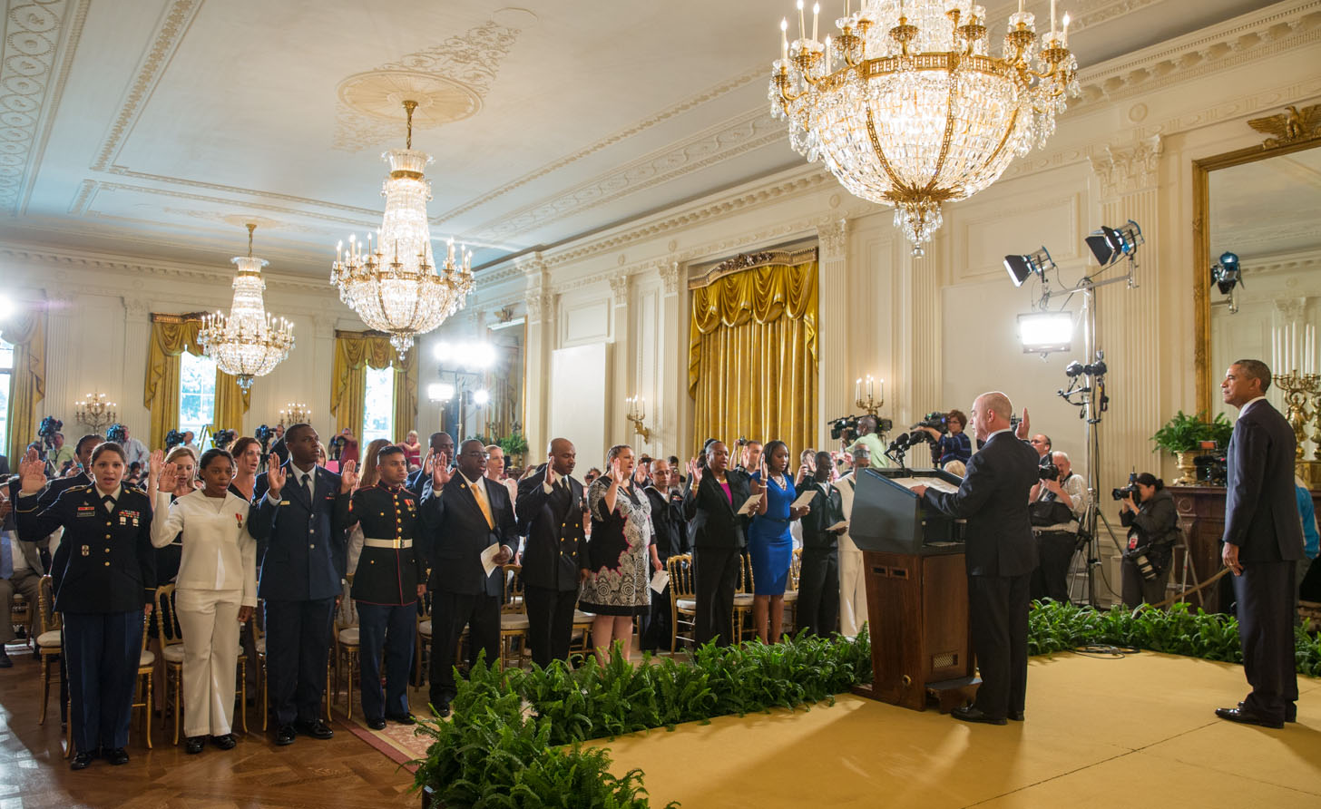 President Barack Obama listens as Deputy Secretary Alejandro Mayorkas, Department of Homeland Security administers the Oath of Allegiance during a naturalization ceremony